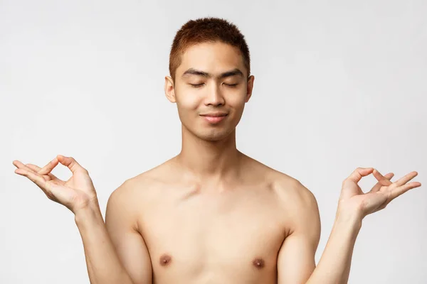 Beauty, people and home concept. Close-up portrait of happy, relieved asian man standing naked over white background, close eyes and smiling, meditating to stay relaxed and calm — Stock Photo, Image