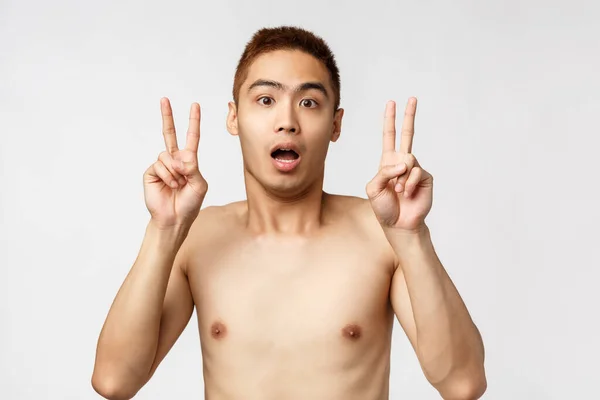 Beauty, people and home concept. Shocked young asian man with naked torso, showing peace sign or quotation marks, gasping startled, hear strange news, express disbelief, white background — Stock Photo, Image