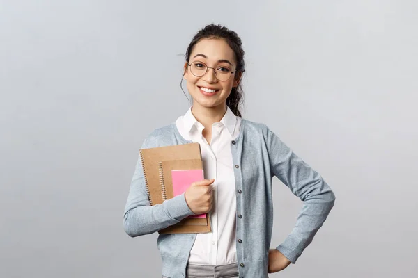 Education, teachers, university and schools concept. Upbeat happy female tutor likes teaching students, standing enthusiastic with prepared study material, hold notebooks smile broadly — Stock Photo, Image