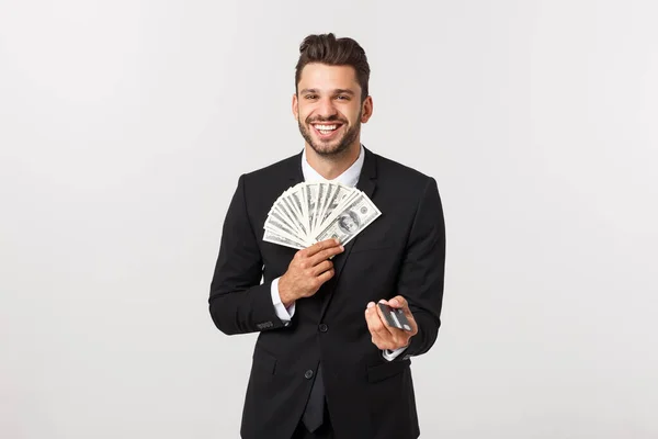 Retrato de un hombre feliz sonriente sosteniendo un montón de billetes de dinero y mostrando la tarjeta de crédito aislada sobre fondo blanco . — Foto de Stock