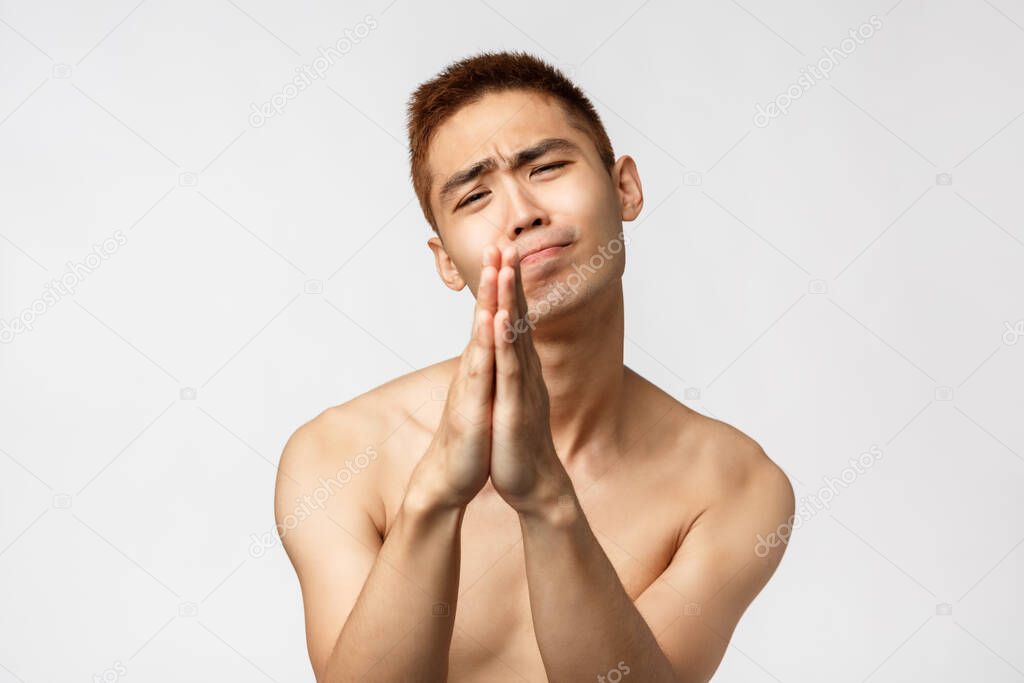 Beauty, people and home concept. Close-up portrait of clingy asian man with naked torso begging for help, clasp hands and asking favour, smiling need help or lend favour, white background