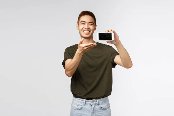 Teknoloji, online yaşam tarzı ve iletişim konsepti. Mutlu ve neşeli Asyalı adam cep telefonuyla bir şey tanıt, uygulamayı göster, akıllı telefon ekranını göster ve gülümse. — Stok fotoğraf