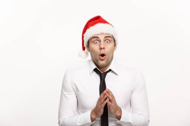 Noel kavramı - Yakışıklı iş adamı beyaz izole edilmiş arka planda şaşırtıcı bir yüz ifadesiyle Noel Baba şapkası takıyor.
