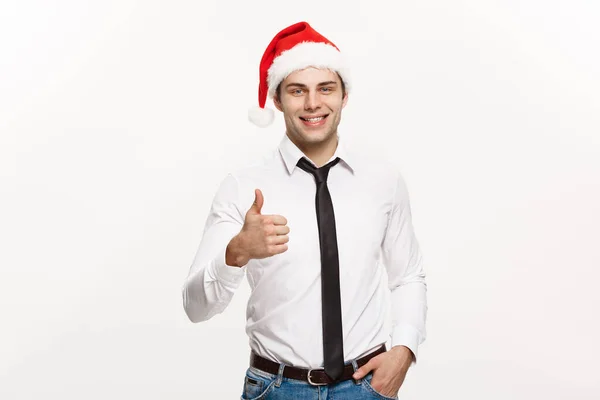 Conceito de Natal - Bonito homem de negócios usar chapéu de Papai Noel mostrando thump up no fundo isolado branco . — Fotografia de Stock