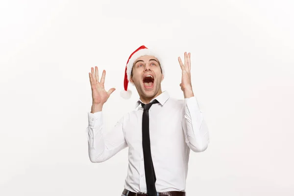 Χριστούγεννα Concept - Όμορφος επιχειρηματίας φορούν καπέλο santa ποζάρουν με εκπληκτική έκφραση του προσώπου σε λευκό απομονωμένο φόντο. — Φωτογραφία Αρχείου