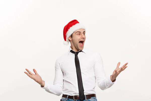Christmas Concept - Przystojny Biznes człowiek nosić santa kapelusz pozowanie z zaskakującym wyrazem twarzy na białym odizolowanym tle. — Zdjęcie stockowe