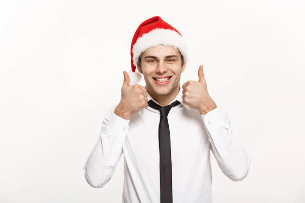 Conceito de Natal - Bonito homem de negócios usar chapéu de Papai Noel mostrando thump up no fundo isolado branco . — Fotografia de Stock