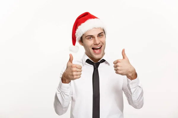 Conceito de Natal - Bonito homem de negócios usar chapéu de Papai Noel mostrando thump up no fundo isolado branco . — Fotografia de Stock