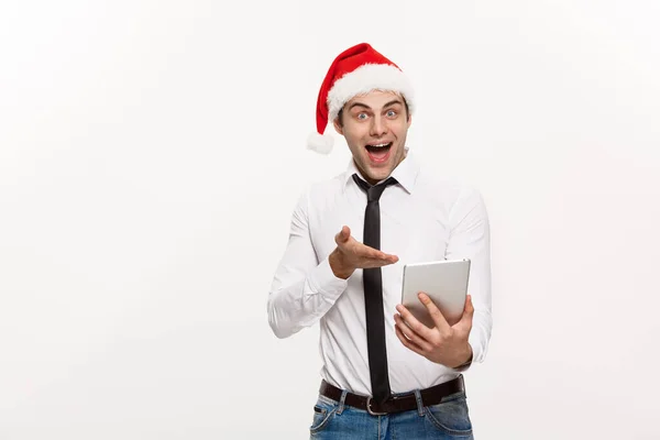 Conceito de Natal - Bonito homem de negócios usar santa chapéu jogando tablet com expressão facial surpreendente . — Fotografia de Stock