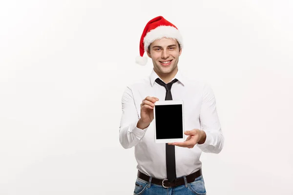 Weihnachtskonzept - Schöner Geschäftsmann präsentiert etwas auf mobilem Bildschirm feiern frohe Weihnachten und ein glückliches neues Jahr tragen Weihnachtsmütze. — Stockfoto