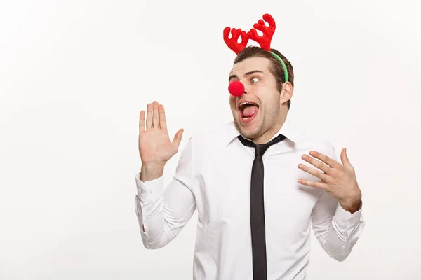 Christmas Concept - Hombre de negocios guapo que usa diadema de reno haciendo expresión facial divertida . — Foto de Stock