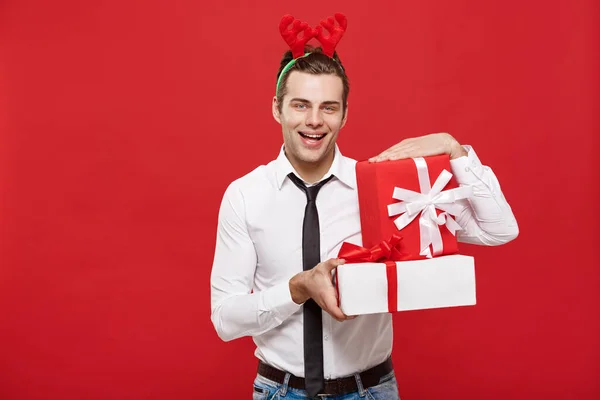 Weihnachtskonzept - Fröhlich fröhlicher junger Geschäftsmann mit dekorativem Geschenk auf rotem Hintergrund. — Stockfoto