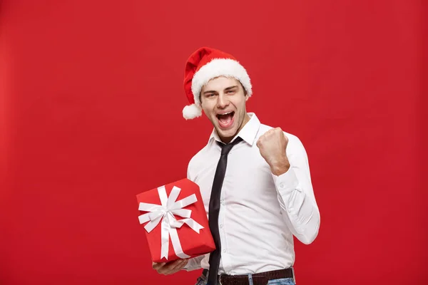 Christmas Concept - Porträt glücklicher Weihnachtsmann Geschäftsmann begeistert mit seinem Geschenk vor rotem Hintergrund. — Stockfoto