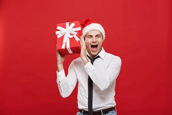 Christmas Concept - Porträt glücklicher Weihnachtsmann Geschäftsmann begeistert mit seinem Geschenk vor rotem Hintergrund. — Stockfoto