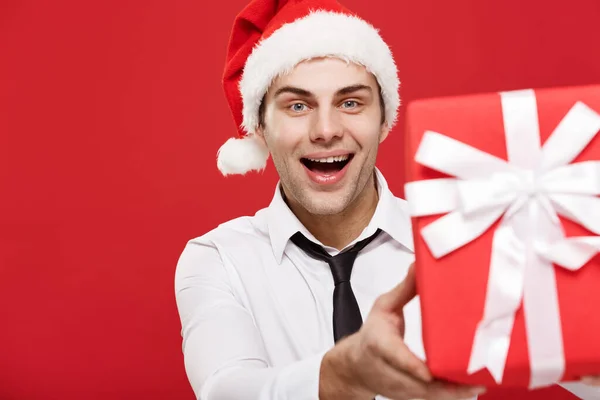 Concepto de Navidad - retrato primer plano de Santa Navidad hombre de negocios sobre fondo rojo dando regalo rojo a la cámara . — Foto de Stock