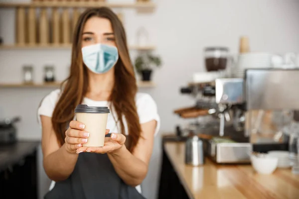 Business Owner Concept - Beautiful Caucasian Barista in face mask offers disposable take away hot coffee at the modern coffee shop — Stock Photo, Image