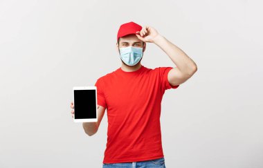Çevrimiçi alışveriş, dağıtım, teknoloji ve yaşam tarzı konsepti. Gülümseyen teslimatçı elinde bir şey gösteren tablet sunuyor. Beyaz stüdyo arka planında izole edilmiş..