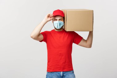 Teslimat Konsepti: genç beyaz yakışıklı teslimatçı omuzunda bir kutu tutuyor. Gri arkaplan üzerinde izole.