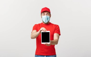 Çevrimiçi alışveriş, dağıtım, teknoloji ve yaşam tarzı konsepti. Gülümseyen teslimatçı elinde bir şey gösteren tablet sunuyor. Beyaz stüdyo arka planında izole edilmiş..