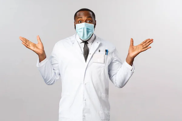 Gefeliciteerd, je bent genezen. Portret van een gelukkige en opgeluchte, lachende Afrikaans-Amerikaanse mannelijke arts in witte jas, handen zijwaarts gespreid vrolijk, kijk verrast en blij patiënt genezen — Stockfoto