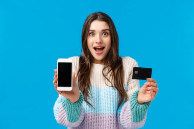 Gülümseyen, heyecanlı ve büyülenmiş genç bir kadın havalı yeni uygulamalardan, bankacılık başvurularından, depozitodan ya da nakitten bahsediyor. Akıllı telefonu kameraya, kredi kartına, sırıtışına bakarak tutuyor.