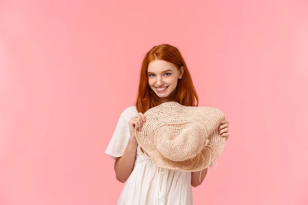 Menina coquete seduzindo alguém com olhar atrevido afetuoso, brincando segurando chapéu de palha, olhar de baixo da testa câmera de olhar sensual, sorrindo sorridente, de pé fundo rosa — Fotografia de Stock