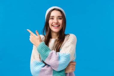 Alışveriş, satış ve kış tatili konsepti. Neşeli, sevimli Avrupalı esmer kadın, güzel gülüşü, sol üst köşesini işaret ediyor ve gülümseyen kamera bize inanılmaz indirimli tekliften bahsediyor.