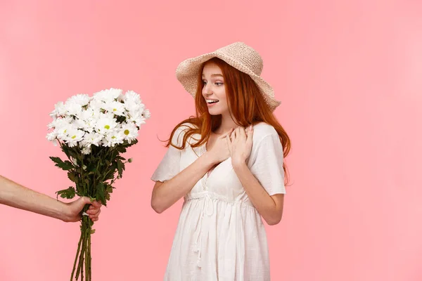 Romance, momentos tiernos y encantadores, concepto de relación. Tocado suspiro y asombrado linda pelirroja seductora chica, recibir hermoso regalo, mirando a la mano dando su ramo de flores blancas — Foto de Stock