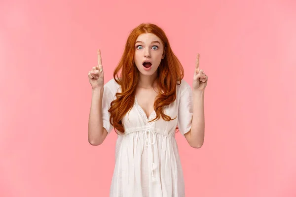 Have you seen it. Overwhelmed, excited attractive redhead female showing friend cool thing, discuss amazing news, pointing fingers up and look astonished camera with opened mouth — 스톡 사진