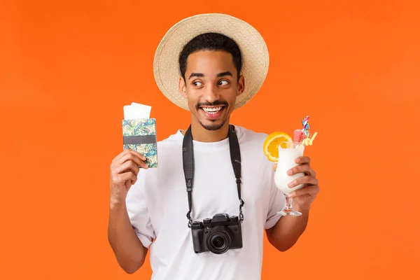흥분, 놀라움, 여행 컨셉트. 유쾌하게 재미있는 아프리카 계 미국인 남성 학생, 비행 티켓 과 칵테일로 여권을 들고 즐겁게 웃으며, 카메라와 모자를 가지고 마침내 휴일을 보낸다. — 스톡 사진