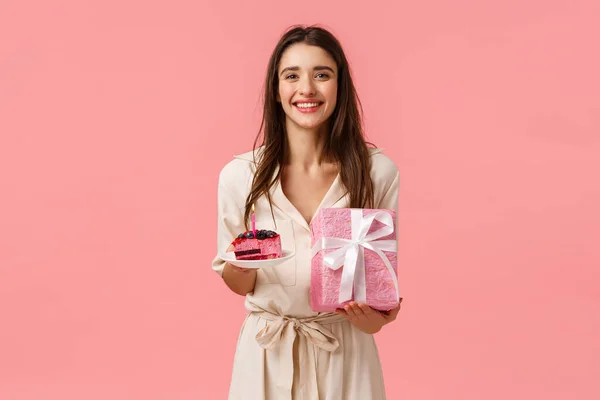 Chica del día B se siente feliz y optimista, disfrutando de la celebración. Atractiva hembra caucásica recibir regalos, la celebración de delicioso pedazo de pastel, regalo envuelto, sonriendo alegremente, de pie fondo rosa — Foto de Stock