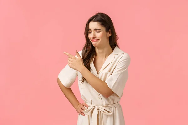 Upset silly brunette caucasian girl in dress, crying and sobbing pointing upper left corner, regret missed opportunity, feeling uneasy or heartbroken, standing pink background distressed — Stock Photo, Image