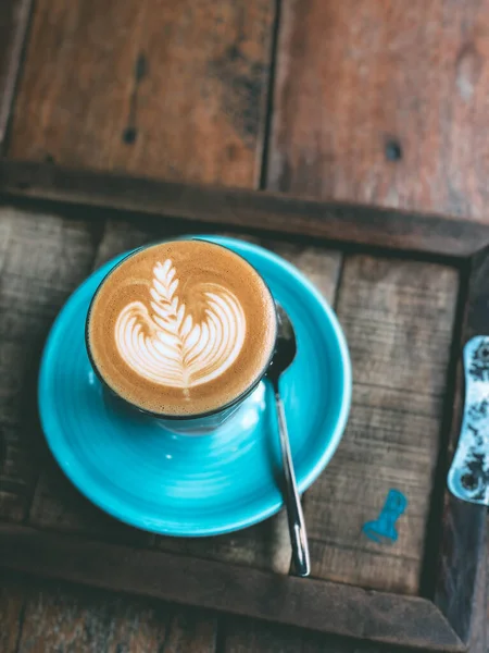 Filiżanka gorącej kawy sztuki latte na zabytkowym drewnianym stole. — Zdjęcie stockowe