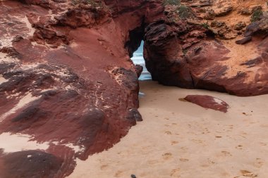 Bulutlu hava ışığında sahilde kızıl okyanus kayaları. Praia da Bordeira. Carrapareira, Portekiz 'de Algarve Sahili, Atlantik Okyanusu