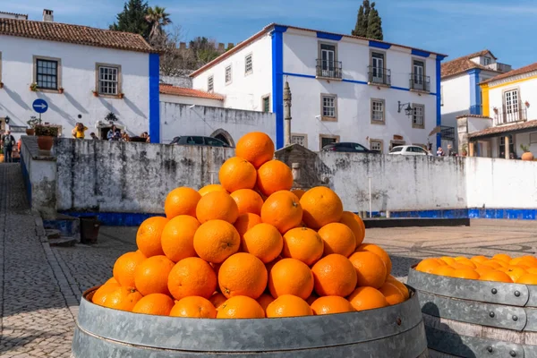 Barrels of oranges in the square next to the church of Santa Maria, Obidos, Portugal
