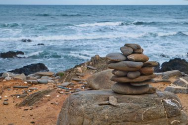 Plajdaki taş piramit Praia do Canal, Portekiz köyü Arrifana kıyısında.