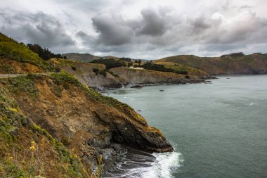 San Francisco kıyı şeridi. Sausalito, California, ABD 'deki Marin Burunları' ndaki kayalıklardan görülen Point Bonita Deniz Feneri yakınlarındaki okyanus ve sahil kayalıkları..
