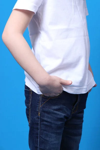Pige sætte sine hænder i lommerne på hans jeans. isoleret på blå baggrund - Stock-foto