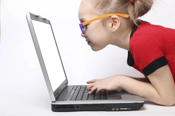 Meisje kijkt op de laptop en te typen op het toetsenbord. geïsoleerde witte achtergrond. oranje bril — Stockfoto