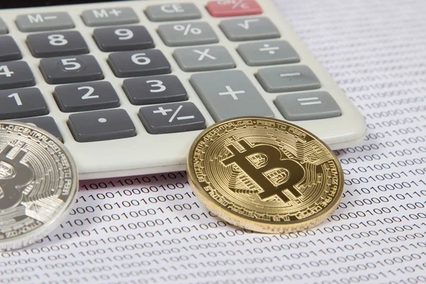 Goud en zilver bitcoin ligt op een witte calculator Stockfoto