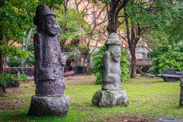 Deux idoles de pierre (Dolharubang, les "pierres de grand-père") à Jeju Mokgwana, le plus ancien bâtiment restant à Jeju pour l'ancien bureau du gouvernement central où le magistrat Joseon Période de Jeju de 1392 à 1910 — Photo