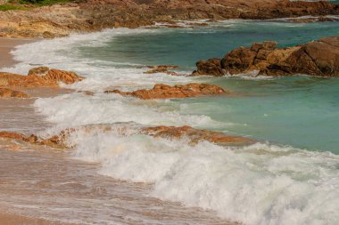 Güzel beyaz kabarcıklar sahilde okyanus dalgaları seashore tarafından yaratılmıştır. Okyanus dalgaları sahilde kayalara çarptı