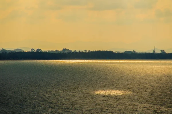 Beautiful sunrise over the sea in the morning on cloudy day that sun beams break through the clouds. Sun beaming through clouds with urban landscape, if you zoom in will see the small fishing boats.