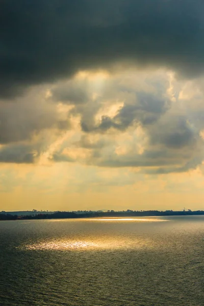 Beautiful sunrise over the sea in the morning on cloudy day that sun beams break through the clouds. Sun beaming through clouds with urban landscape, if you zoom in will see the small fishing boats.