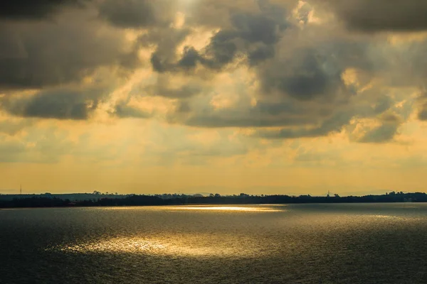 Beautiful sunrise over the sea in the morning on cloudy day that sun beams break through the clouds. Sun beaming through clouds with urban landscape, if you zoom in will see the small fishing boats.