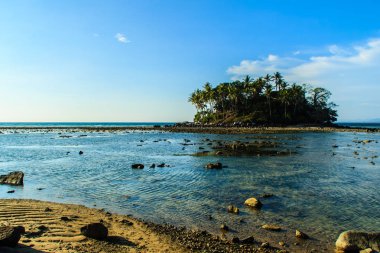 Rock plaj ve deniz suyu mavi gökyüzü ve bulutlu gün arka plan gerilemiştir zaman ağaç ile yalnız uzak ada