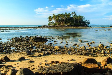Rock plaj ve deniz suyu mavi gökyüzü ve bulutlu gün arka plan gerilemiştir zaman ağaç ile yalnız uzak ada