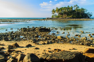Rock plaj ve deniz suyu mavi gökyüzü ve bulutlu gün arka plan gerilemiştir zaman ağaç ile yalnız uzak ada