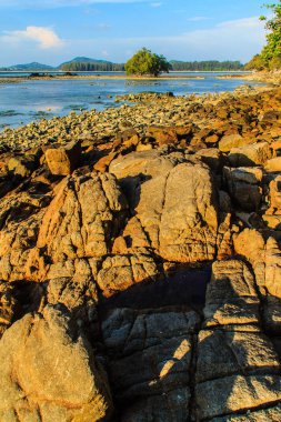 Rock plaj ve deniz suyu mavi gökyüzü ve bulutlu gün arka plan gerilemiştir zaman ağaç ile yalnız uzak ada