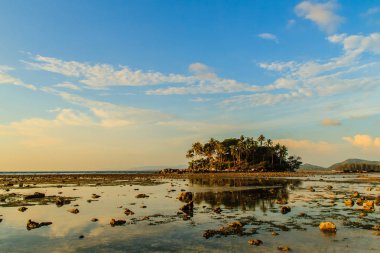 Rock plaj ve deniz suyu mavi gökyüzü ve bulutlu gün arka plan gerilemiştir zaman ağaç ile yalnız uzak ada